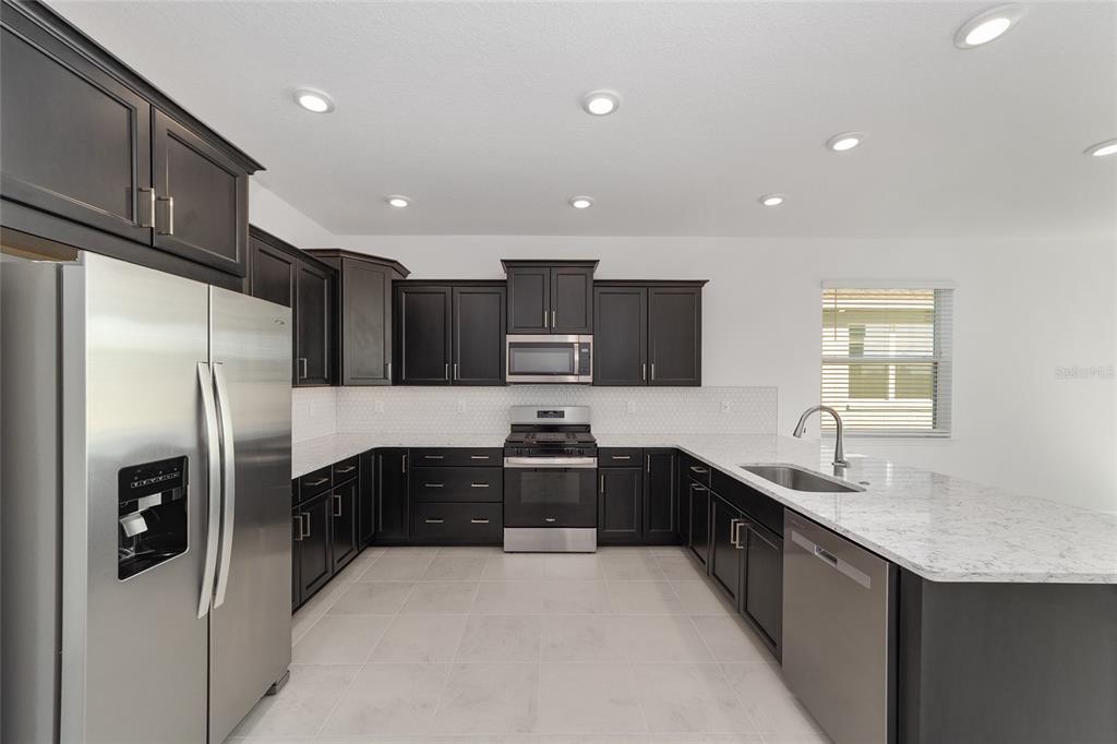 7276 Southwest 58th Place Road Ocala, FL 34474 - Photo 20 of 44 a kitchen with stainless steel appliances granite countertop a refrigerator a sink a stove a microwave and island