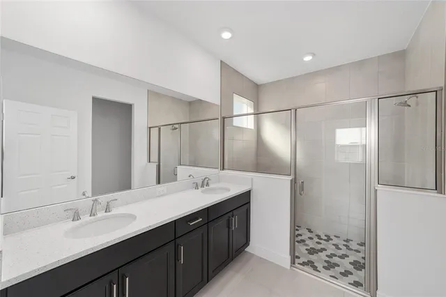 a bathroom with a double vanity sink mirror and shower