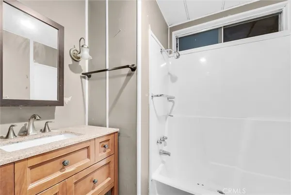 a bathroom with a granite countertop sink a mirror and shower