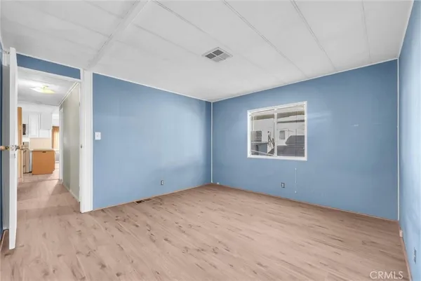 a view of an empty room with wooden floor and a bathroom