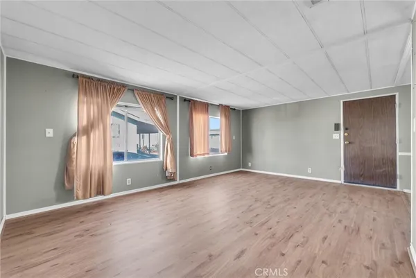 a view of an empty room with a window and wooden floor