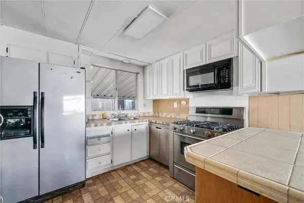 a kitchen with stainless steel appliances a stove sink microwave refrigerator and cabinets