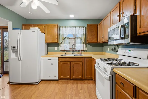 a kitchen with granite countertop a refrigerator a sink dishwasher and white cabinets with wooden floor