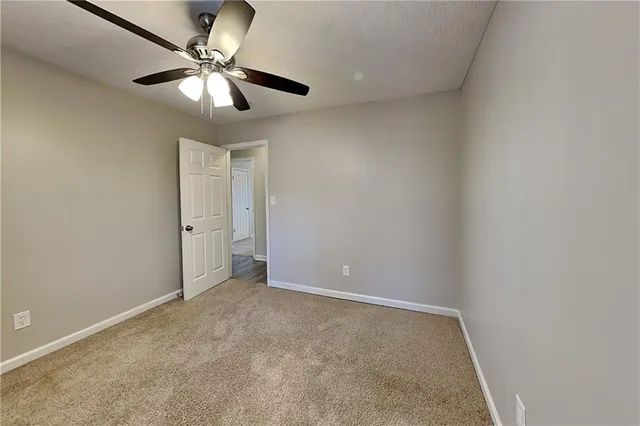an empty room with a chandelier fan and a ceiling fan