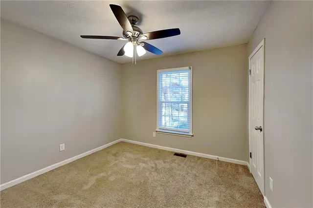 an empty room with a window and a fan