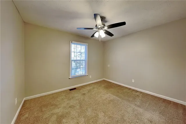an empty room with a window and a fan