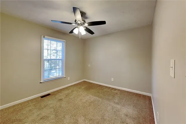 an empty room with a window and a fan