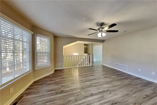 a view of an empty room with window and wooden floor