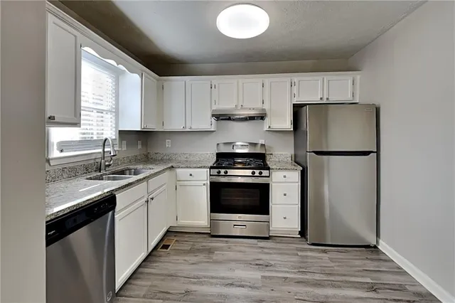 a kitchen with a refrigerator sink and cabinets