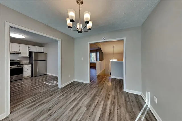 a view of a hallway with wooden floor and a kitchen