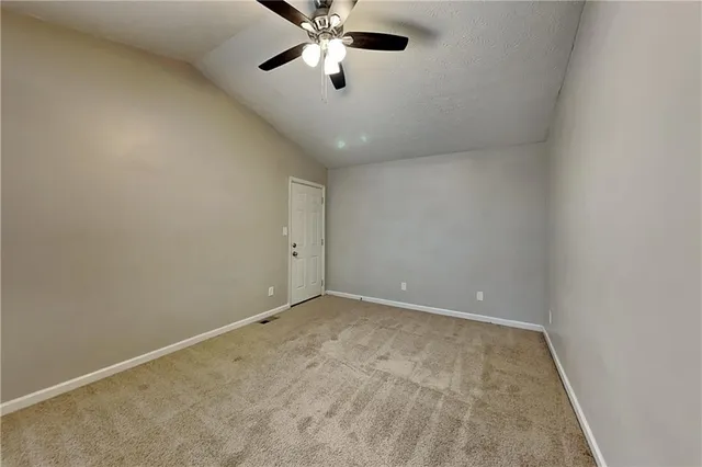 an empty room with a ceiling fan and carpet