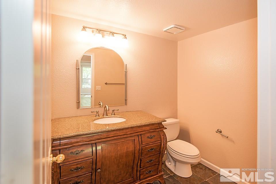 245 Falling Water Court Reno, NV 89519 - Photo 14 of 20 a bathroom with a granite countertop toilet a sink and a mirror