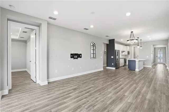 a view of a hallway with wooden floor and a kitchen