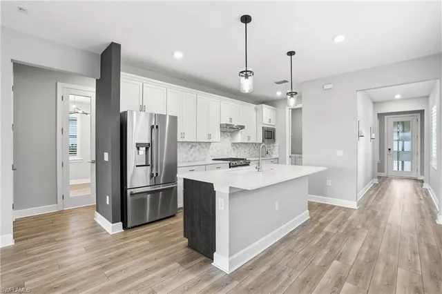 a kitchen with stainless steel appliances kitchen island granite countertop a refrigerator a sink and wooden floors