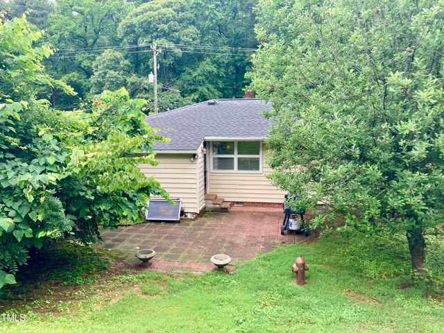 a backyard of a house with plants and large trees