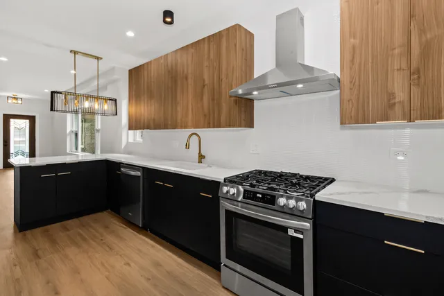 a kitchen with stainless steel appliances a stove a sink dishwasher and a refrigerator with wooden cabinets