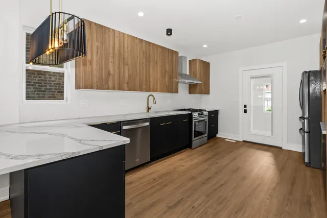 a kitchen with stainless steel appliances granite countertop a sink dishwasher a stove and a refrigerator with wooden floor