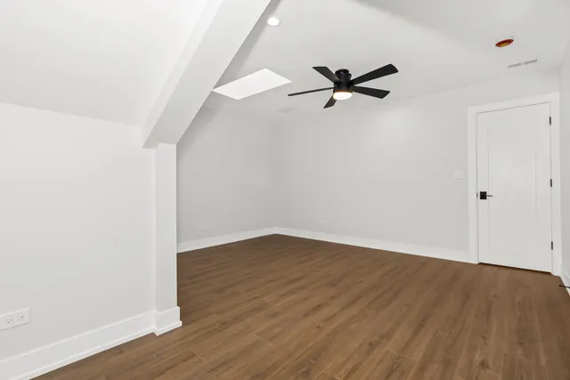 an empty room with wooden floor ceiling fan and windows