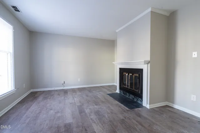 an empty room with wooden floor and fireplace