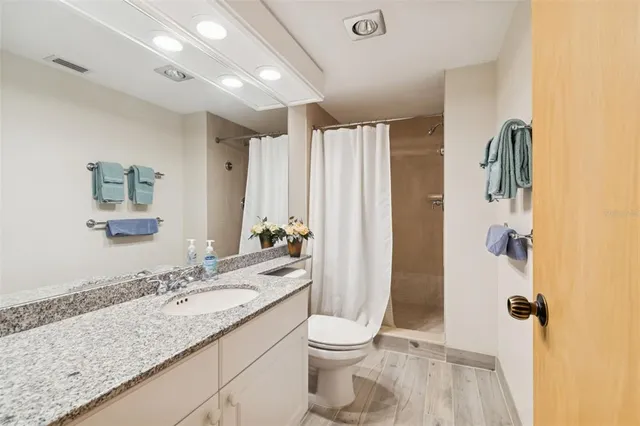 a bathroom with a granite countertop sink toilet and shower
