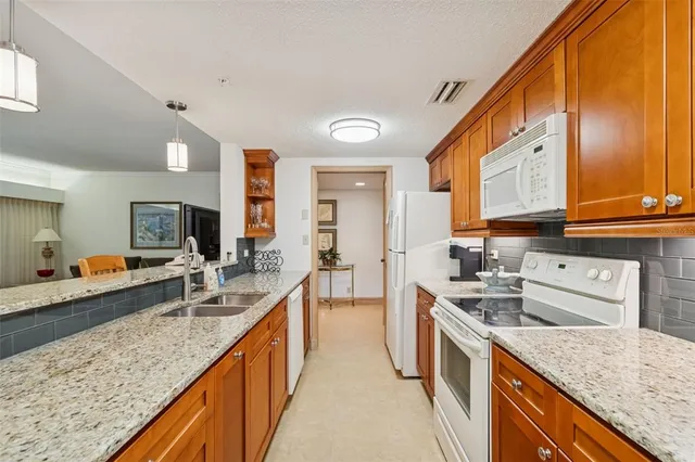 a kitchen with stainless steel appliances kitchen island granite countertop a dining table chairs and white cabinets