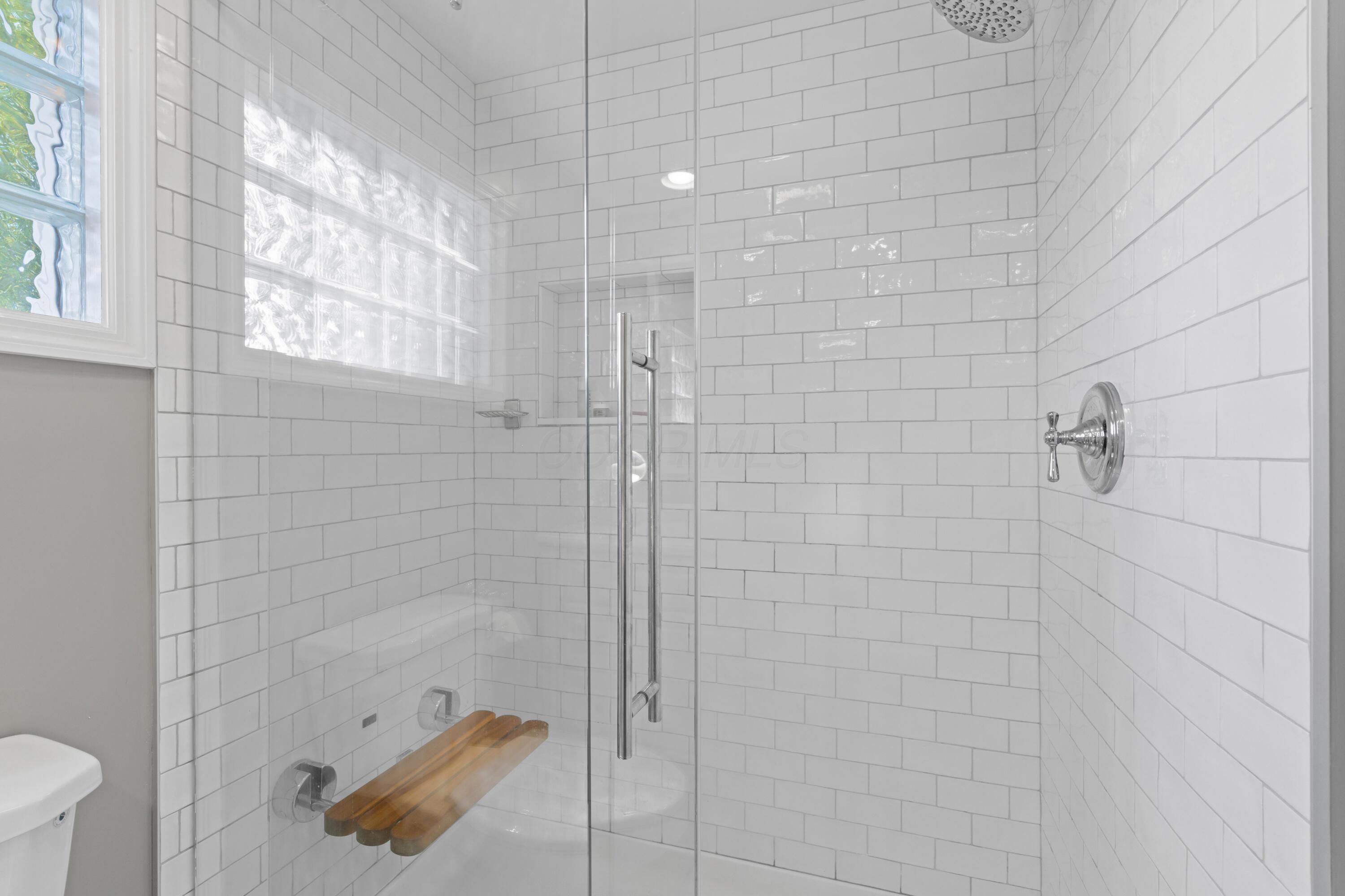 41 Aldrich Road Columbus, OH 43214 - Photo 33 of 52 Large Primary Suite with two closets, built-in storage bench, perfect for a reading nook! En Suite with remodeled walk-in shower, also done by Dave Fox®, complete with glazed subway tile surround, chrome fixtures with rainshower showerhead and built-in teakwood bench!