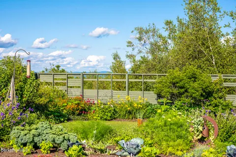 a view of a chair and tables under an umbrella in the garden