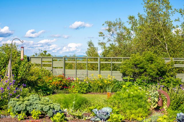 a view of a chair and tables under an umbrella in the garden