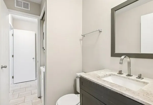 a bathroom with a granite countertop sink toilet and mirror