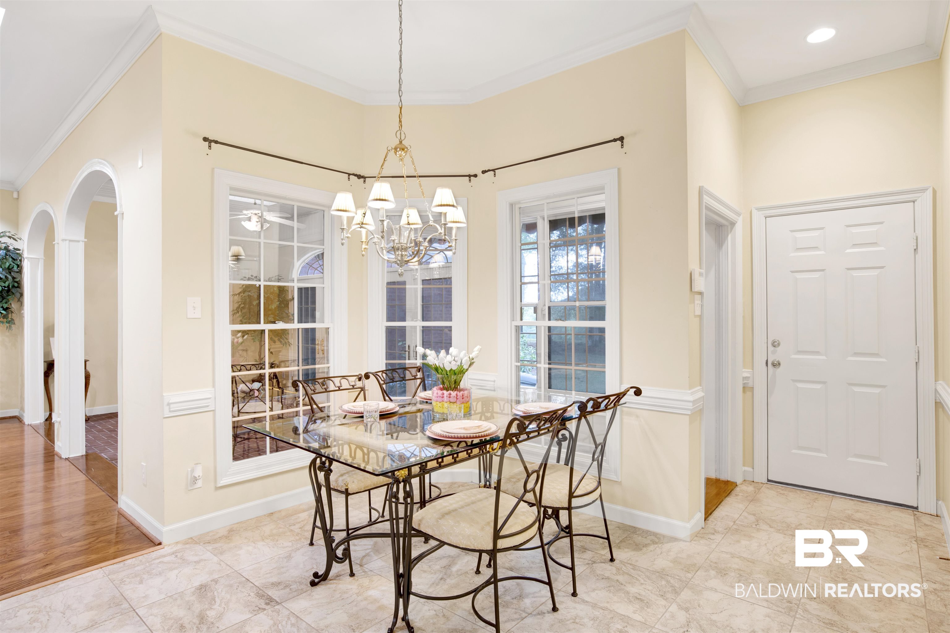 106 Old Mill Road Fairhope, AL 36532 - Photo 25 of 49 Dining space featuring baseboards, crown molding, arched walkways, and a chandelier