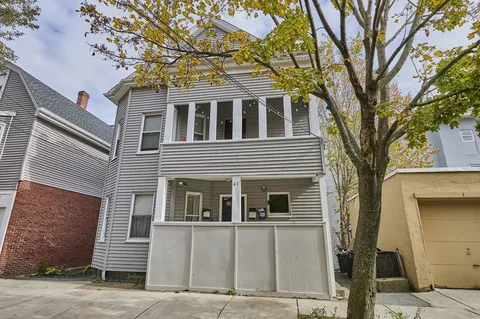 a front view of a house with a tree