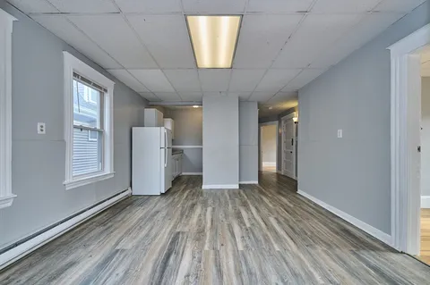 a view of empty room with wooden floor and window