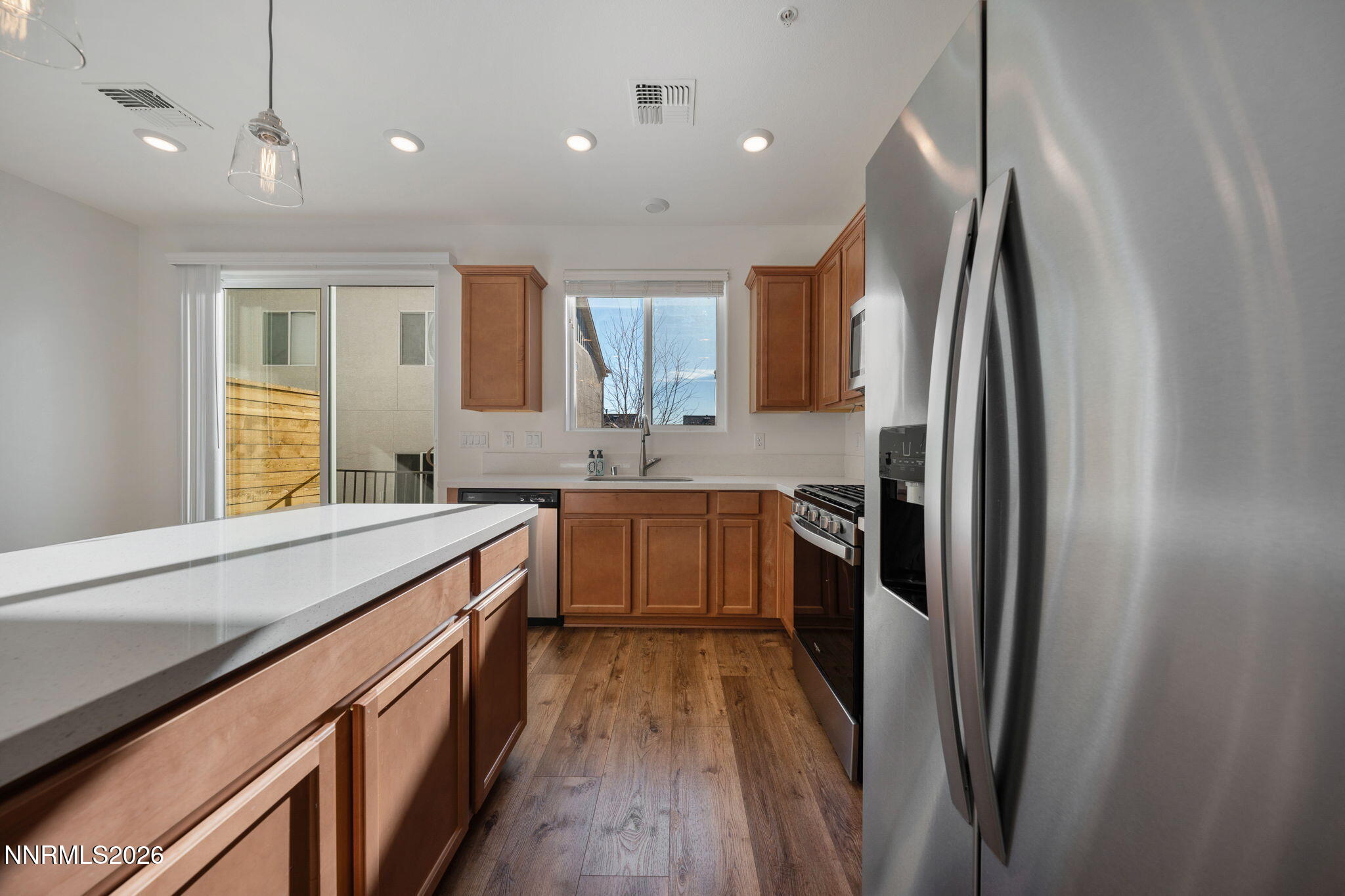 530 Gloria May Lane Reno, NV 89503 - Photo 9 of 34 a kitchen with stainless steel appliances granite countertop a refrigerator a sink dishwasher a stove and a dining table with wooden floor