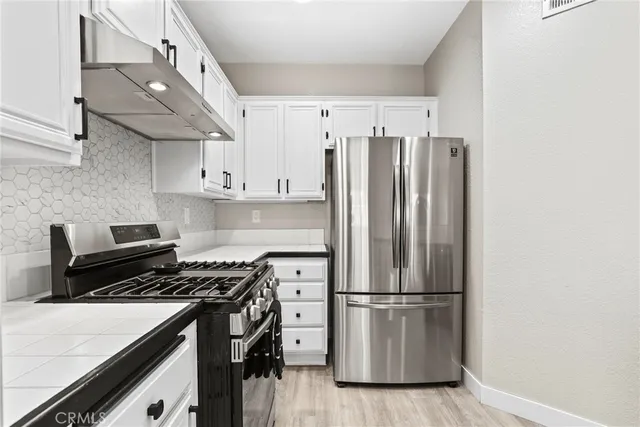 a kitchen with stainless steel appliances a refrigerator a stove and wooden floor