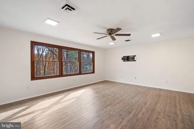 a view of an empty room with a window and wooden floor