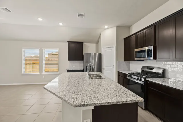 a kitchen with kitchen island granite countertop stainless steel appliances a sink stove and refrigerator