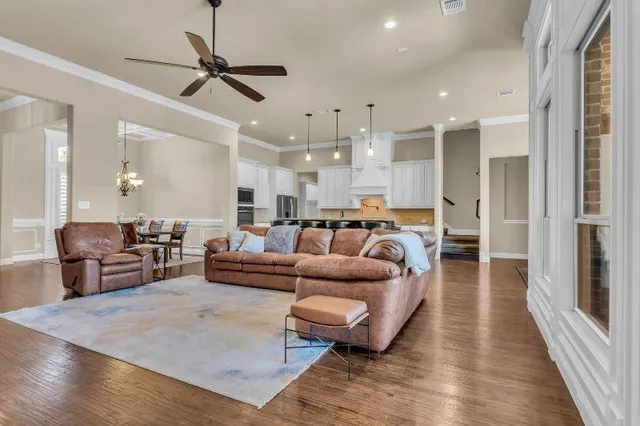 a living room with furniture kitchen view and a wooden floor