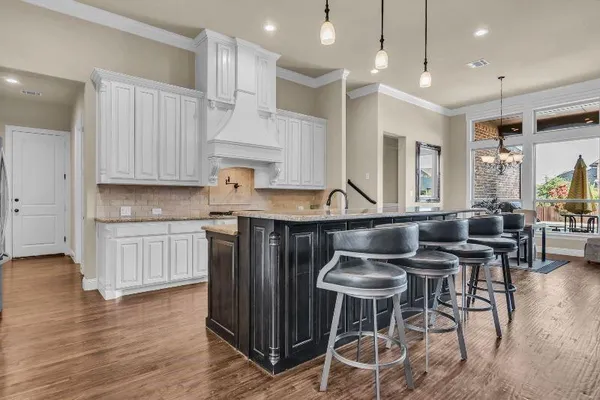 a kitchen with stainless steel appliances granite countertop a table chairs stove and wooden cabinets