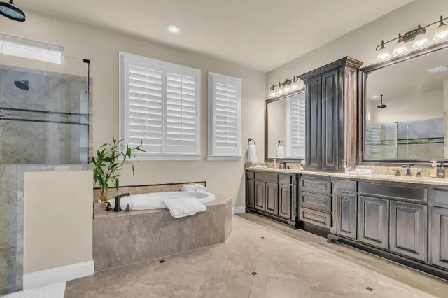 a large spacious bathroom with a double vanity sink a large mirror and a bathtub
