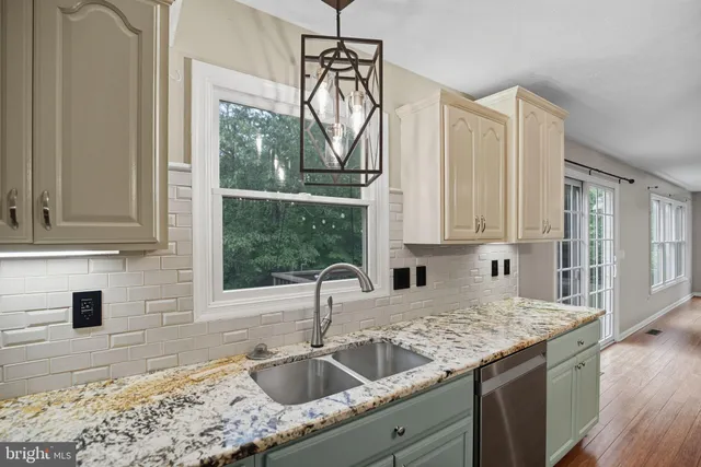 a kitchen with granite countertop a sink a counter top space and cabinets