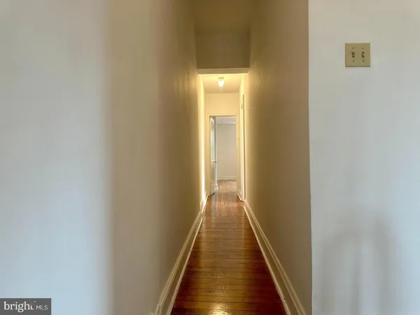 a view of a hallway with wooden floor and a bathroom