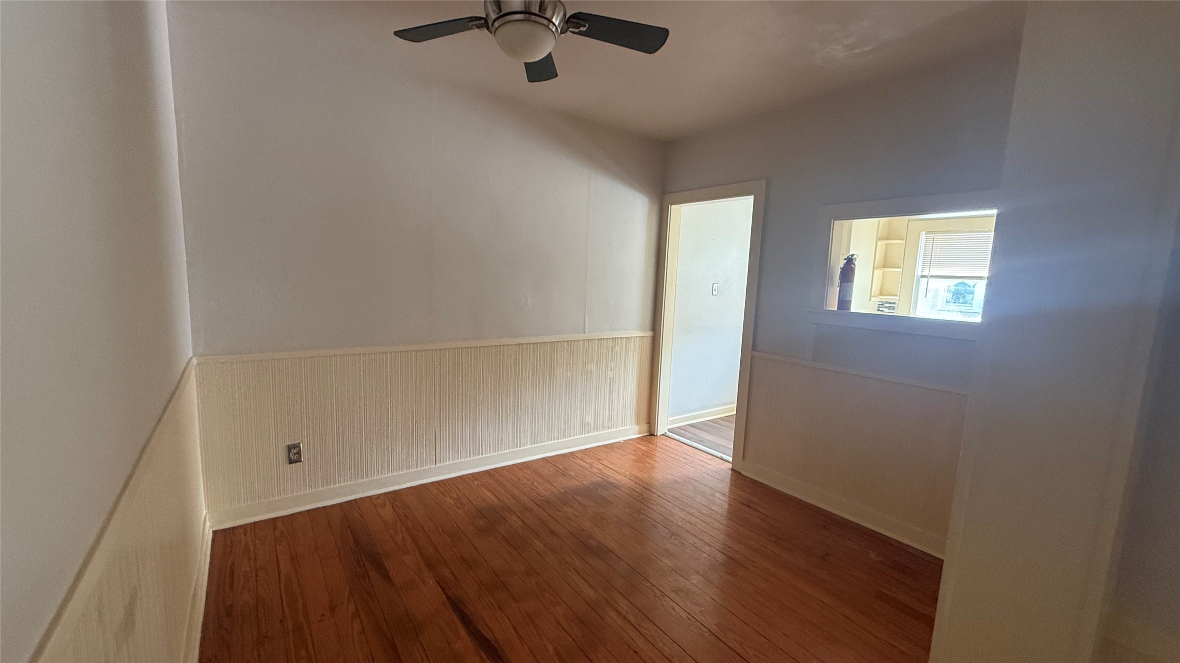 an empty room with a hardwood and ceiling fan