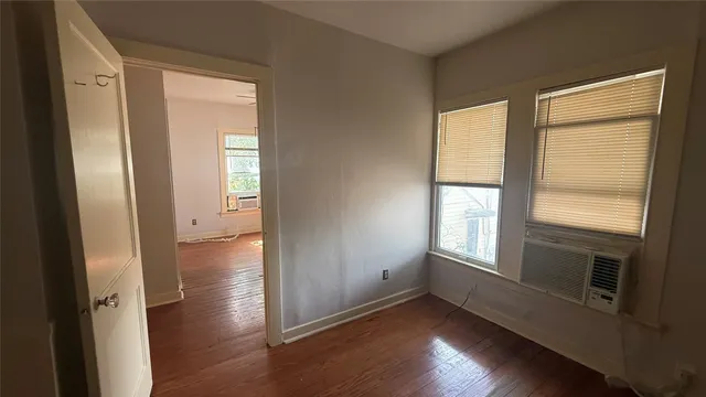 a view of an empty room with wooden floor and a window