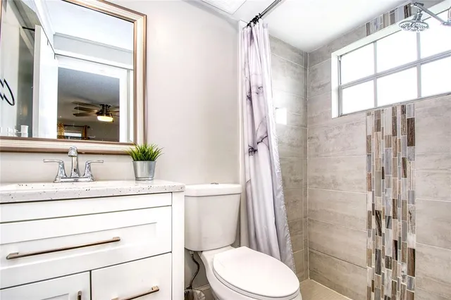 a bathroom with a granite countertop sink toilet a mirror and shower
