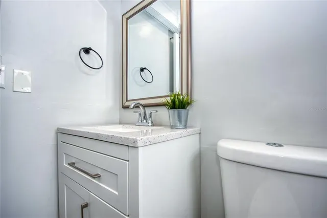 a bathroom with a granite countertop toilet sink and mirror