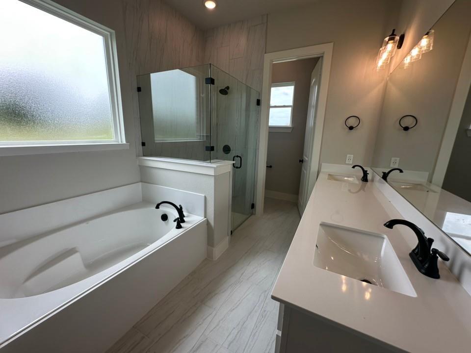 390 Cobb Road Leonard, TX 75452 - Photo 17 of 26 Modern bathroom featuring a soaking tub with matte black fixtures, a walk-in shower with glass enclosure, dual vanity with undermount sinks and quartz countertops, and wood-finish tile flooring