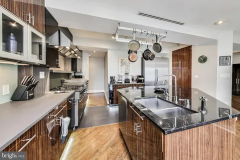 a kitchen with stainless steel appliances granite countertop a sink a stove and a wooden cabinets