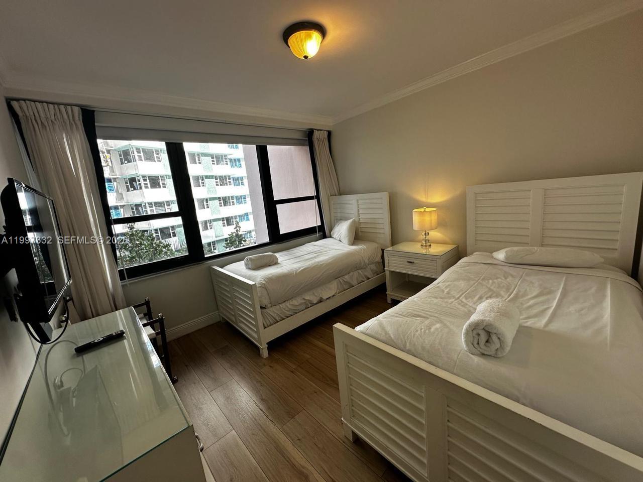 5225 Collins Avenue, Unit 614 Miami Beach, FL 33140 - Photo 3 of 8 a bedroom with two beds and a flat screen tv