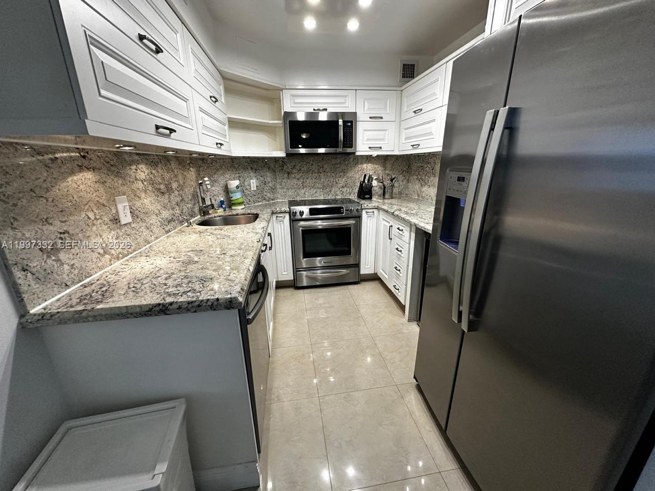 5225 Collins Avenue, Unit 614 Miami Beach, FL 33140 - Photo 6 of 8 a kitchen with granite countertop a refrigerator and a stove