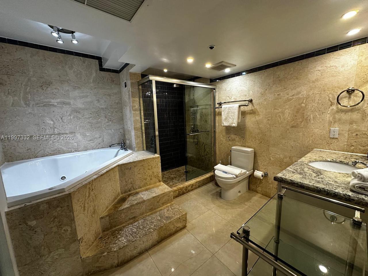 5225 Collins Avenue, Unit 614 Miami Beach, FL 33140 - Photo 7 of 8 a bathroom with a granite countertop sink a toilet and shower